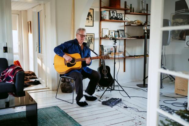 Mand spiller guitar i stuen